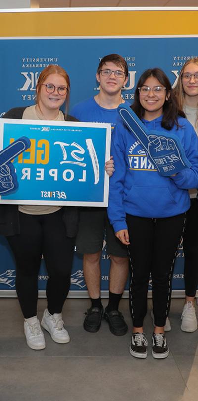 students pose for a photo holding up a first generation sign